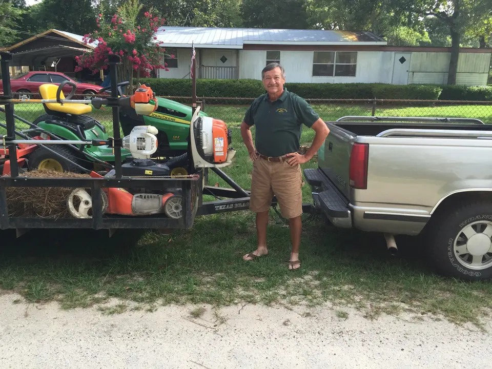 Truck and trailer loaded with mowers parked in front of a house