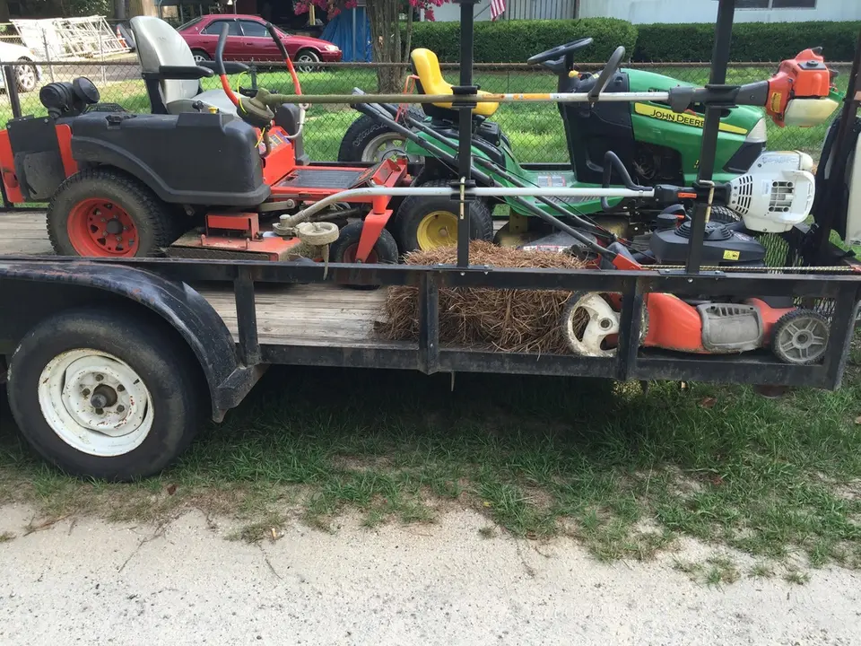 Trailer with two mowers, a trimmer and bales of pine straw
